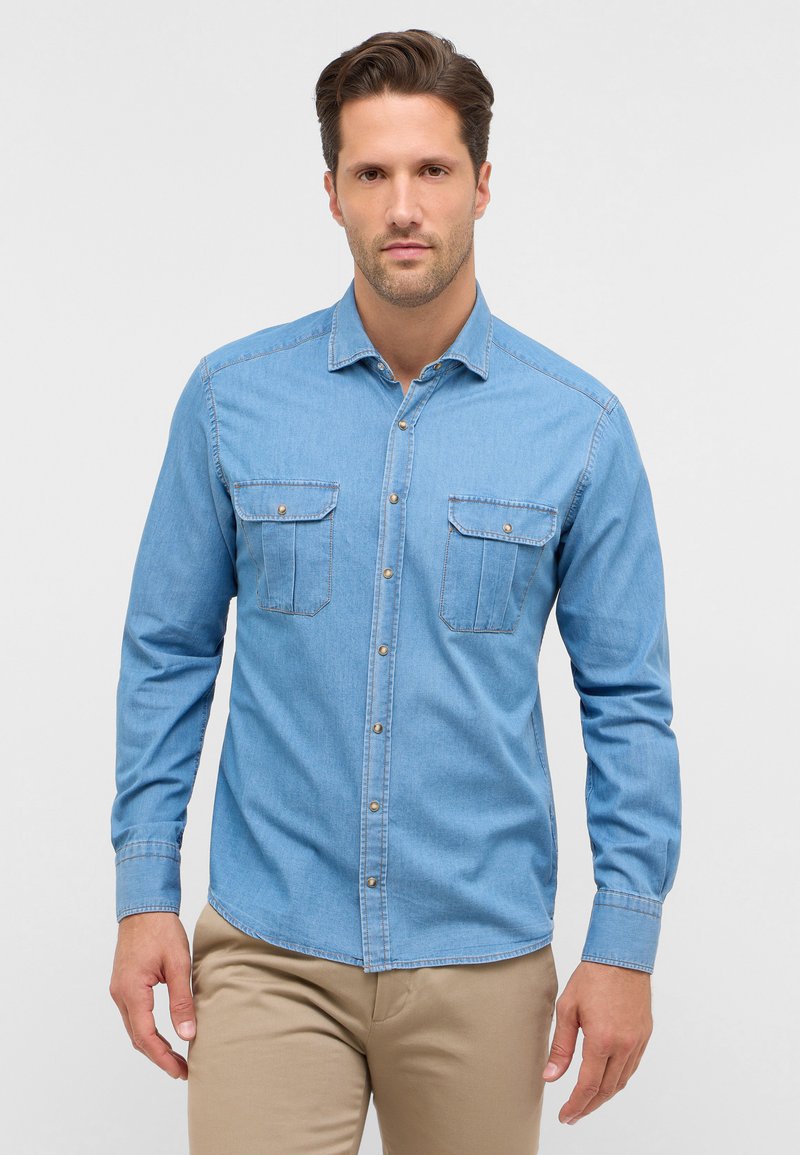 Camicia in denim azzurro chiaro con maniche lunghe, due tasche sul petto, chiusura anteriore con bottoni e dettagli di cucitura a contrasto. Texture liscia.