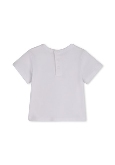 T-shirt pour bébé à manches courtes blanc avec trois boutons-pression au dos et un col rond, posé à plat sur un fond blanc.