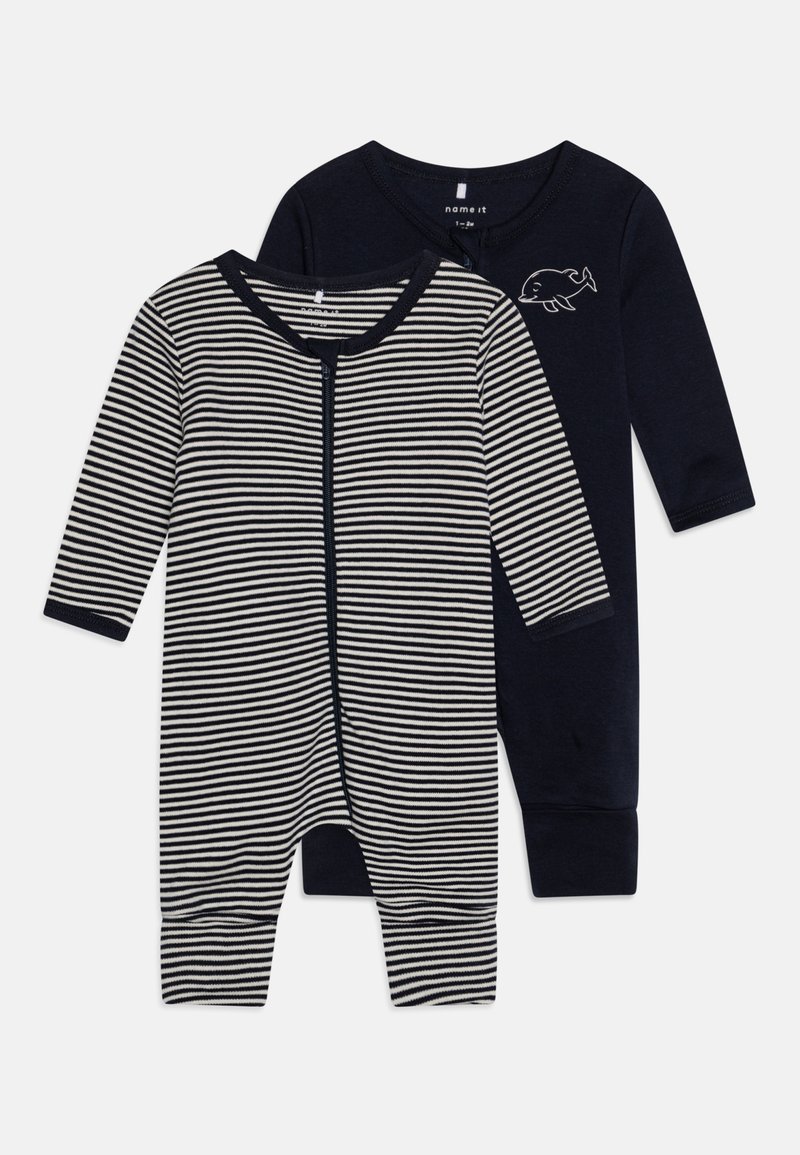 Δύο βρεφικά φορμάκια: το ένα μωβ με γραφικό μιας φάλαινας, το άλλο ριγέ σε ναυτικό και κρέμ, με μπροστινό φερμουάρ και μακριά μανίκια.