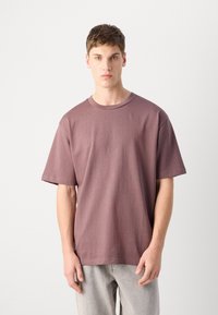 T-shirt de manga curta em malva suave, feito de um tecido macio com um corte descontraído, apresentando um colarinho redondo e uma textura suave.