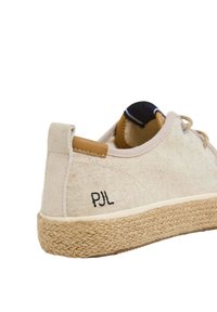 Scarpa in tela beige con suola in juta intessuta, caratterizzata dal logo nero "PJL" e un accento in pelle sul tallone. Design a punta arrotondata.