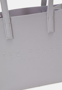 Sac fourre-tout gris texturé avec logo embossé "Ted Baker London". Dispose de deux poignées et d'un design structuré, adapté à un usage quotidien.