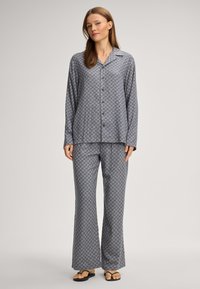 Šedý vzorovaný pyžamový set obsahující košili na knoflíky s dlouhým rukávem a kalhoty širokého střihu, vyrobený z měkké tkaniny s geometrickým designem.