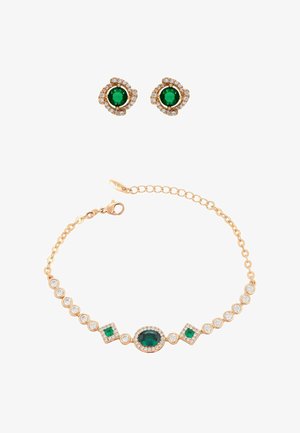 Kultasävyinen korusarja, jossa on smaragdinvihreitä ja kirkkaita jalokiviä. Rannekoru, jossa on ovaaleja ja neliönmuotoisia kiviä, sekä vastaavat pyöreät niittikorvakorut.