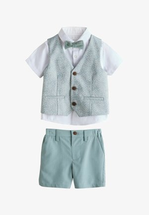 Baltas trumpomis rankovėmis marškinėliai su šviesiai mėlynu gėlėtu liemene, derančia peteliške ir vienspalviais šviesiai mėlynais šortais mažam berniukui.