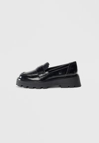 Mustad musta platvormiga loafers, millel on paks tallaga, pennistrap, dekoratiivsed perforatsioonid ja poleeritud nahkviimistlus, esitatud külgvaates.