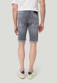 Grijze denim shorts met opgerolde zoom, met achterzakken en een label op de tailleband, gecombineerd met witte en marineblauwe sneakers.