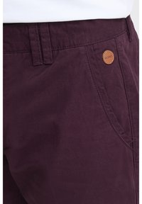 Pantalones cortos de algodón burdeos con una textura suave, que cuentan con un bolsillo frontal y una etiqueta de logo de cuero en la cintura.