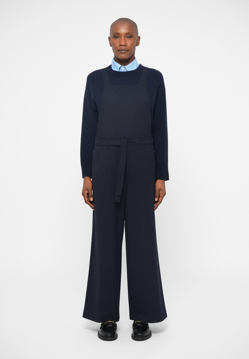 Mornarji modri široki hlače z pasom in predpasnikom, nameščenim na svetlo modro srajco s ovratnikom. Gladka tekstura z diskretnim dizajnom.