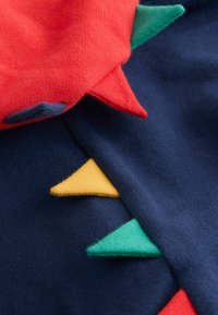 Sweter z czerwonymi i zielonymi trójkątnymi akcentami na granatowym tle, wykonany z miękkiego, teksturowanego materiału o dopasowanym kroju.