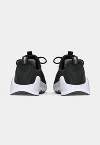 Zwarte sportieve schoenen met een gladde stoffen bovenkant, witte gestructureerde zool en treklussen bij de hiel voor gemakkelijk aan- en uittrekken. Minimalistisch ontwerp.