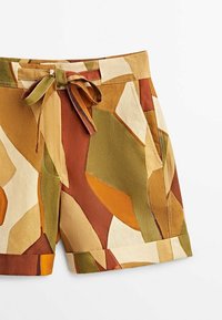 Shorts made of lightweight fabric in a multicolored abstract pattern featuring green, brown, and beige. Tied waist with a front bow detail.