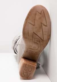 Bottine en suède gris avec un talon en bois épais et une semelle en caoutchouc texturé arborant un motif en zigzag. Taille 37 indiquée sur la semelle.