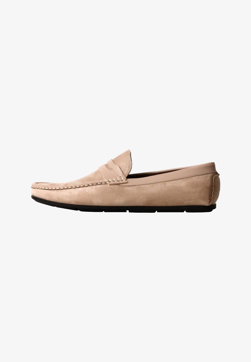 Mocassin homme en daim beige avec semelle en caoutchouc noire et détails cousus le long du bord supérieur.