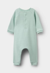 Jasno miętowy kombinezon z miękkiego materiału, z długimi rękawami, okrągłym dekoltem oraz zapięciem na guziki z przodu, z prążkowanymi mankietami i nogawkami.