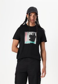 Black cotton t-shirt featuring a graphic design with the text "WEEKEND OFFENDER." Short sleeves and a relaxed fit. No prominent texture.