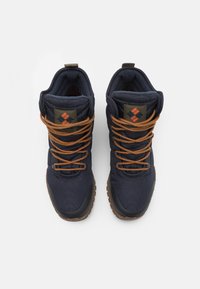 Bottines de randonnée bleu marine foncé en tissu résistant avec des lacets orange, des cols rembourrés et une semelle en caoutchouc texturé. Patch logo sur la languette.