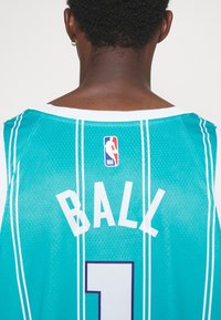 Teal koripallopaita, jossa on valkoisia yksityiskohtia, selässä nimi "BALL" ja numero "1". NBA-logo ylhäällä. Rakenteellinen kangas.