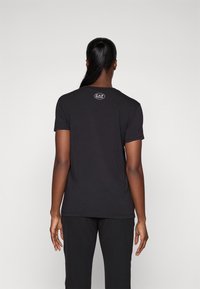 Zwarte t-shirt met korte mouwen, gemaakt van zachte stof. Heeft een ronde halslijn en een klein EA7-logo op de bovenrug. Minimalistisch ontwerp.