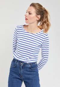 Blauw en wit gestreepte langemouwen T-shirt met een ronde halslijn, gecombineerd met hoogwaist blauwe spijkerbroeken. Glad materiaal, ontspannen pasvorm.