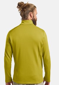 Pull-over à manches longues pour homme en tissu texturé vert citron, avec un col montant et un design de couture à plat.