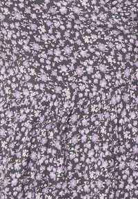Vestido floral com pequenas flores roxas e brancas sobre um tecido cinza escuro, com cintura franzida e textura suave.