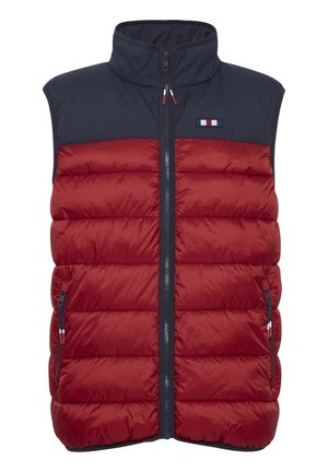 Piros és tengerész-kék puffos mellény vertikális steppeléssel, magas gallérral, elülső cipzárral és két oldalsó cipzáras zsebbel. Logófolttal rendelkezik.