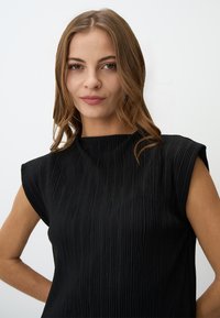 Schwarzes Top mit einem strukturierten, plissierten Design. Verfügt über kurze Ärmel und einen hohen Kragen, was eine klare Silhouette schafft.
