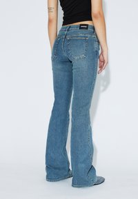 Uppblåst blå jeans i denim, med en midja som sitter på höften, bakfickor och en något urblekt textur.