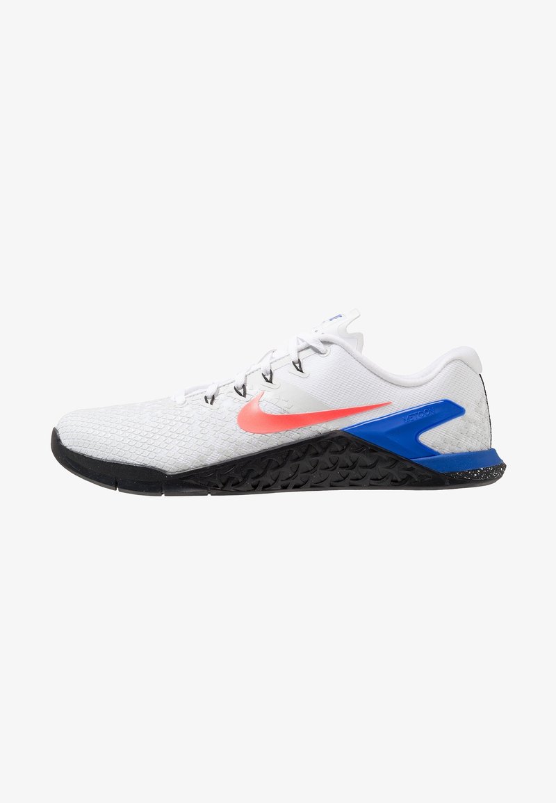 Zapatillas de entrenamiento Nike con una parte superior texturizada blanca, swoosh rosa, acentos azules y una suela negra con patrón. Presentan un diseño de lazada segura.