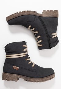 Botines negros de material sintético, con cordones color beige, cierre de cremallera y suela de goma texturizada con un diseño de dibujo pronunciado.
