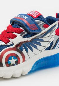 Rød og blå atletisk sko med netoverdel, forsynet med et Captain America-design, velcro-rem og en gennemsigtig blå sål.