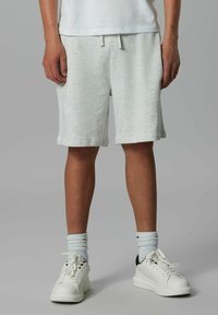 Shorts en coton gris clair avec une taille élastique et un cordon de serrage. Assortis avec des baskets blanches et des chaussettes côtelées bleu clair.