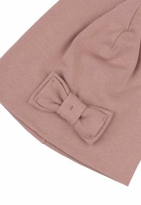 Berretto rosa lavorato a maglia con una finitura testurizzata, caratterizzato da un evidente dettaglio a fiocco. Il tessuto sembra morbido ed elastico.