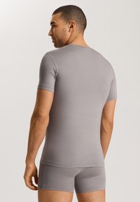 Camicetta grigia a maniche corte attillata realizzata in tessuto liscio, abbinata a pantaloni corti coordinati; entrambi presentano un design senza cuciture e una vestibilità aderente.