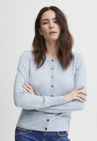 Gaiši zils kardigans, kas izgatavots no mīksta auduma, ar apaļu kakla izgriezumu, ribotām piedurknēm, priekšējo pogu aizdari ar tumšām pogām, pieguļošs dizains.