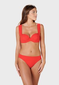 Red bikini set featuring a balconette bra with wide straps, molded cups, and matching low-rise bottoms. Smooth, stretchy fabric with no patterns.
