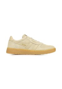 Zapatilla de ante beige con un acabado texturizado, que presenta tres acentos de rayas, diseño de cordones y suela de goma. Logo dorado en el lateral.