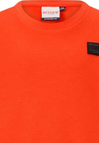Felpa arancione brillante con collo a girocollo realizzata in tessuto morbido, dotata di un colletto a coste e di un piccolo etichetta nera sul davanti.