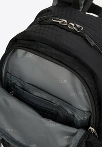 Sac à dos noir texturé avec un motif géométrique, présentant un intérieur gris et plusieurs poches. La quincaillerie des zips est en argent.