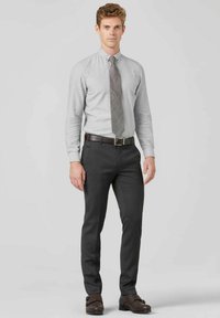 Chemise boutonnée gris clair, cravate grise à motifs, pantalon gris foncé et chaussures en cuir brunes texturées avec boucles. Design simple et coupe ajustée.