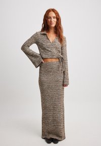 Completo a due pezzi in maglina marrone con texture, caratterizzato da un top avvolgente con maniche a campana lunghe e una gonna lunga fino al pavimento.