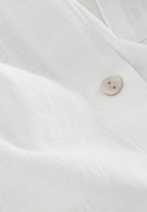 Witte linnen stof met een gestructureerde weving, voorzien van een lichtroze knoopdetail. Zacht, lichtgewicht materiaal. Casual en ademend uiterlijk.