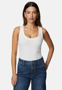 White ribbed tank top with a scooped neckline, paired with high-waisted dark blue denim cargo pants featuring side pockets.