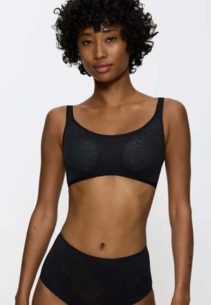 Bralette in pizzo nero con spalline larghe e design senza cuciture, abbinato a slip neri a vita alta, con dettagli sottili di motivi floreali.