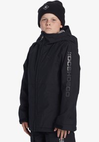 Svart vattentålig jacka med huva, dragkedja fram och kardborreförsedda ärmavslut. Har en framträdande DC Shoes-logotyp tryckt på ärmen. Varmt, hållbart tyg.