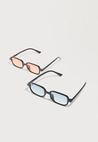 Δύο ζεύγη ορθογώνιων γυαλιών ηλίου, το ένα με σκελετό από καβούρι και πορτοκαλί φακούς, το άλλο με μαύρο σκελετό και μπλε φακούς, πάνω σε λευκή επιφάνεια.