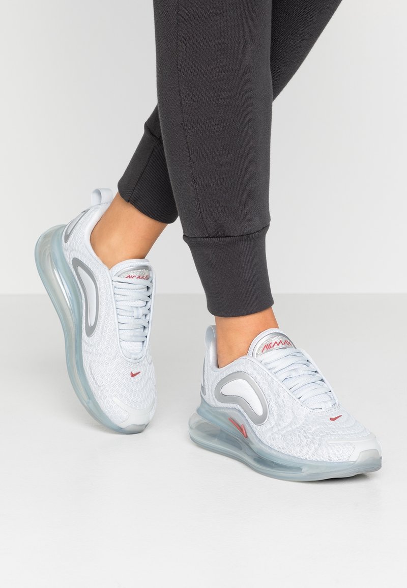 Vita sportskor i vitt med mesh-överdel, vadderad tunga och röda detaljer. Genomskinlig luftkuddar-sula, rund tådesign och texturerad detalj.