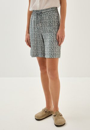 Pantaloni corti a fantasia verde e bianca con vita elastica e dettaglio con cordoncino, caratterizzati da un design geometrico. Stile piatto, sopra il ginocchio.