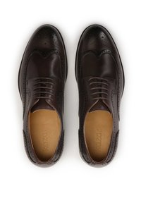 Pantofi brogue din piele maro, cu detalii perforate, vârf rotund și design cu șireturi. Interiorul are o căptușeală bej cu branding.